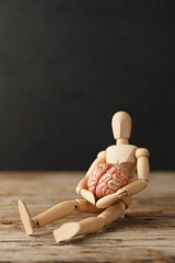 Toy man holds an anatomical brain in his hands. Care and therapy, psychological symptoms. Neuroligic diseases.