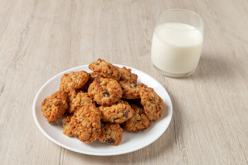 Glasses of milk with cookies on a white plate on a wooden table