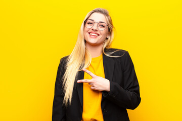 young pretty blonde woman feeling happy, positive and successful, with hand making v shape over...