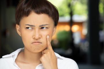 unhappy woman with acne on her cheek face; concept of facial skin care, acne treatment, pimple, zit inflammation