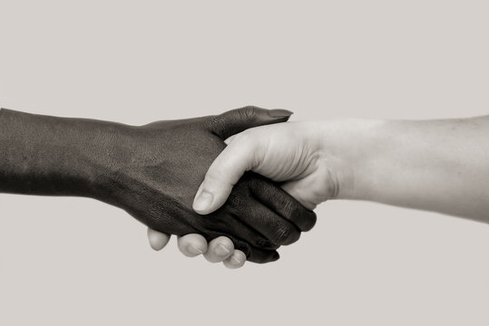 Black and white human hands in joint handshake on an isolated background. The concept of combating racism, friendship and respect between peoples.Selective focus, close-up,black and white photography