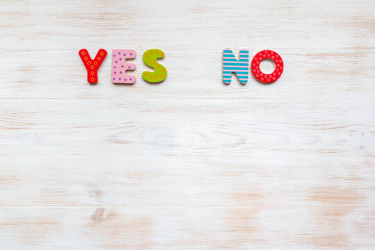 Colored words YES and NO on wooden background