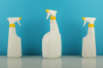 cleaning products in white spray bottles on blue background 