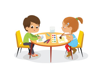 Boy and Girl sit at the round table and draw picture with watercolor and pencils. Drawing activity in the art class. Boy and Girl Draw Pictures with paints and pencils. 