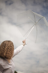 A girl in a white shirt holds an umbrella in her hands and photographs the sky. Rainy and cloudy...