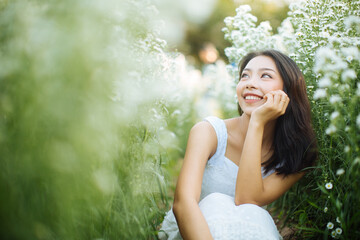 Young beautiful woman in a white dress posing in garden