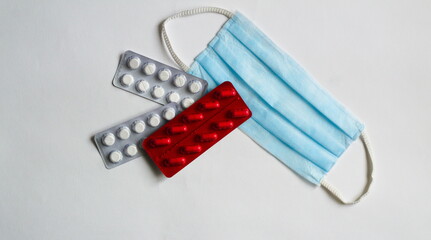 Medical mask, pills in blister packs on a white background