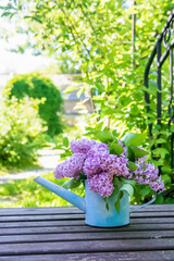 beautiful bouquet of lilacs in garden watering on bridge