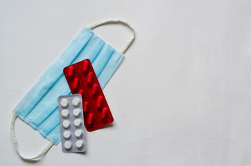 Medical mask, pills in blister packs on a white background