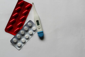 pills, capsules for the treatment of diseases and a thermometer on a white background
