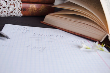 Book and black note with pen. Literature for the holidays and summer. Notes and quotes. Books on the dark table.