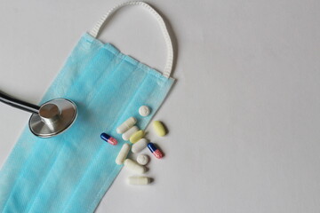 medical mask, stethoscope and pills on a white background