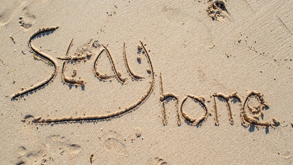 The inscription in the sand. Stay home concept. View from above