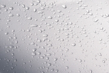 Raindrops on silver bonnet of a car. Condensed water drops on metal car surface