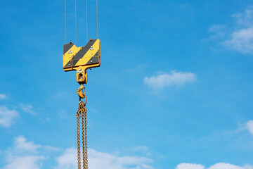 Crane load hook against the sky with trails and chain.