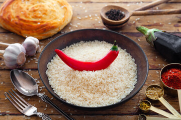 Pilaf ingredients, rice, vegetables, pita, cutlery, spices on rustic background