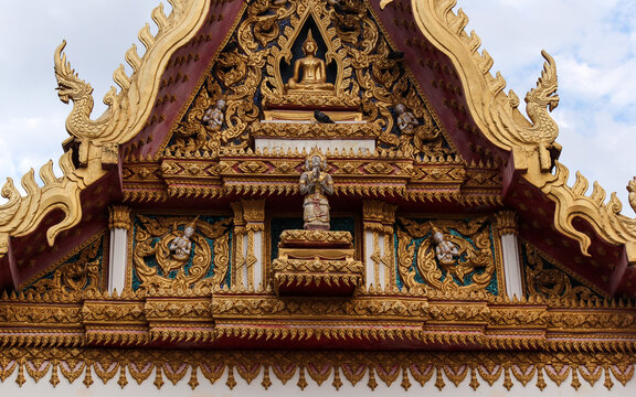 Intensively decorated and golden pediment of a temple building showing various buddha images in Siamese Lao PDR, Southeast Asia