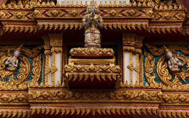 Fototapeta na wymiar Intensively decorated and golden painted detail of a temple building showing various buddha images in Siamese Lao PDR, Southeast Asia