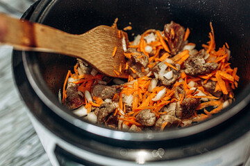 Onions with carrots are fried. Home cooking. Pilaf with meat