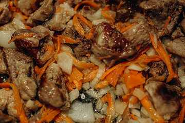 Onions with carrots are fried. Home cooking. Pilaf with meat