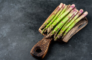 
Raw green asparagus on a cutting board on a stone background with copy space for your text