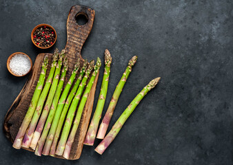 
Raw green asparagus on a cutting board on a stone background with copy space for your text