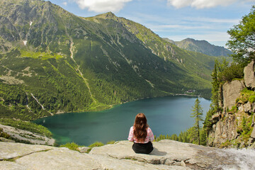 Tourist woman in the mountains looking at lake Morskie Oko. Back view. Adventures in the high mountains. Girl hiking the Tatra National Park, Zakopane, Poland. Carpathian mountains on background. © Khrystyna Bohush
