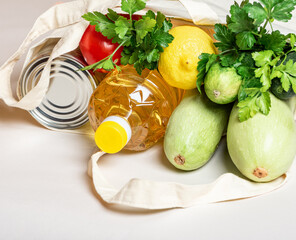 Grocery eco bag with fresh vegetables, canned goods and oil on a white background close-up.  Shopping food supermarket, food delivery for cooking.