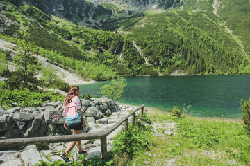 Tourist woman near the mountain lake Morskie Oko. Concept of travel and outdoor activities. Girl traveles the Tatra National Park, Zakopane, Poland. Carpathian mountains on background. - obrazy, fototapety, plakaty