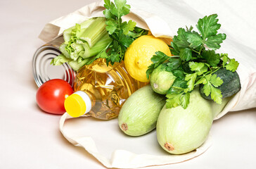 Grocery eco bag with fresh vegetables, canned goods and oil on a white background close-up.  Shopping food supermarket, food delivery for cooking.