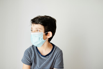 Nine-year-old boy putting on the virus protection mask alone.
