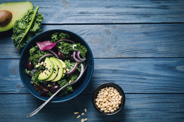 Flat lay composition with tasty fresh kale salad on blue wooden table, space for text. Food photography
