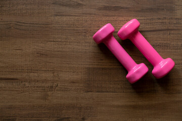 two pink dumbbell on a wooden table background, sport and healthy concept
