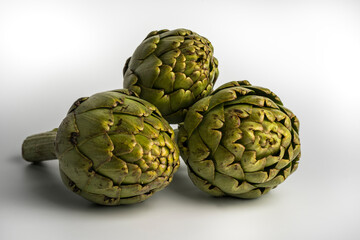 Obraz premium Grupo de tres alcachofas aisladas sobre fondo blanco