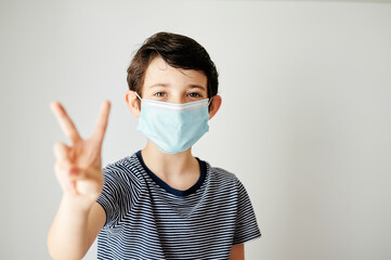 happy boy and with victory sign with her protective mask to avoid contagion against the virus