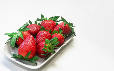 Fresh red strawberries in a white plate on a white background. Isolate
