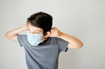 Nine-year-old boy putting on the virus protection mask alone.
