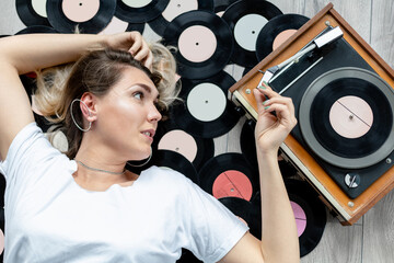 girl listens to vinyl records on an old record player lying on the floor, top view