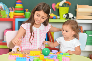 Fototapeta premium Two little girls playing with colorful plastic blocks