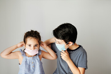 brothers trying to put on a surgical mask to go outside in the confinement due to the coronavirus. social distancing measures to avoid contagion