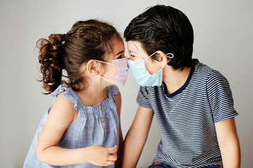 two child playing with mask in coronavirus times. brothers trying to put on a surgical mask to go outside in the confinement due to the coronavirus. social distancing measures to avoid contagion