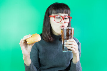 Playful woman opened mouth and drinking cola with ice and hamburger in her hands holding. Enjoy eating concept