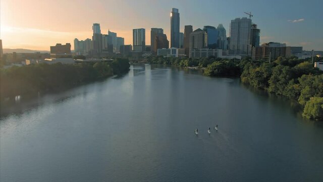 Aerial: Paddleboarding on Lady Bird Lake & downtown Austin at sunrise. Texas, USA