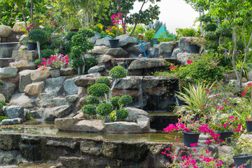 Stone garden with waterfalls and flowers pot decoration in cozy home flower garden on summer.