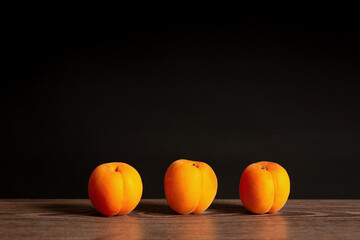 ripe apricots on wooden board and dark background