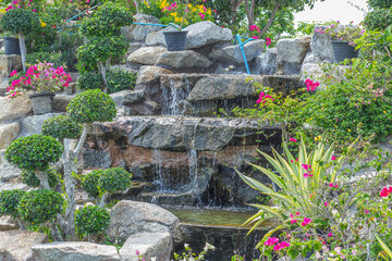 Stone garden with waterfalls and flowers pot decoration in cozy home flower garden on summer.