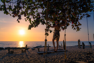 Girl on a swing at sunset on the beach.