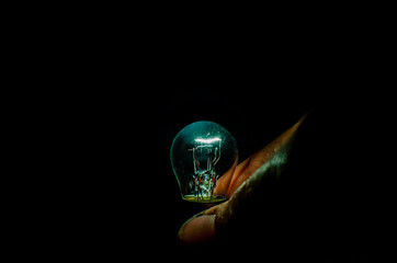 Hand holding dim light bulb in dark