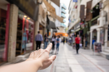 Girl shows finger on a shop of busy tourist street. Selective focus