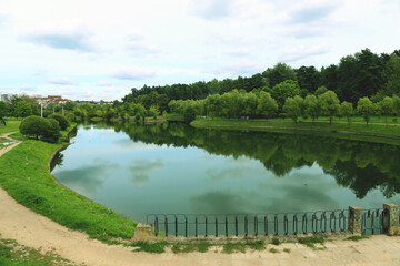 Beautiful landscape of a reservoir against the background of a summer forest and a blue sky with clouds